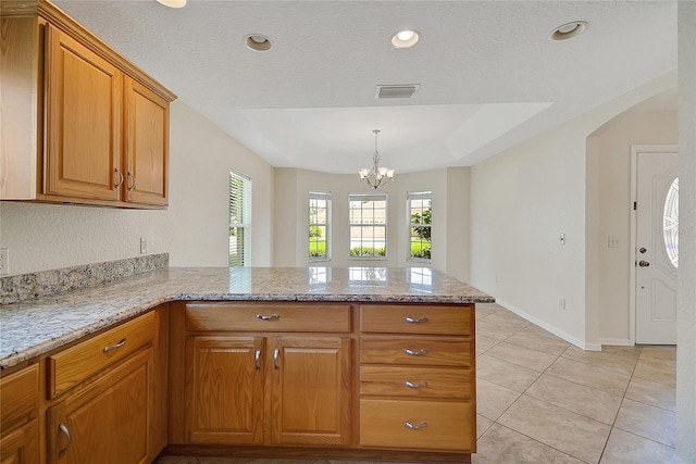 2880 Manor Downs, The Villages, FL 32162 - kitchen with a peninsula, a chandelier, brown cabinets, light stone countertops, and arched walkways