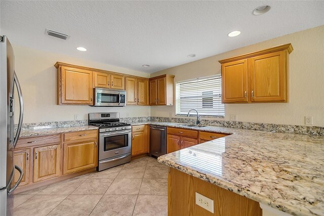 2880 Manor Downs, The Villages, FL 32162 - kitchen with appliances with stainless steel finishes, light stone counters, light tile patterned floors, recessed lighting, and brown cabinets