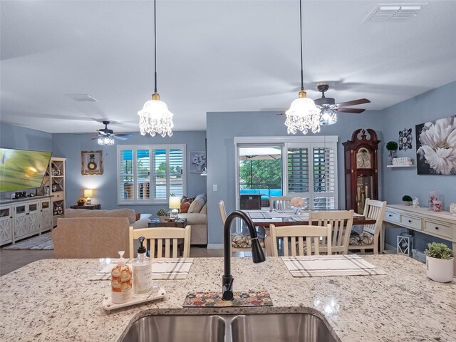 2710 Lilyturf Ct, Tavares, FL 32778 - kitchen with ceiling fan, a chandelier, light stone countertops, and hanging light fixtures