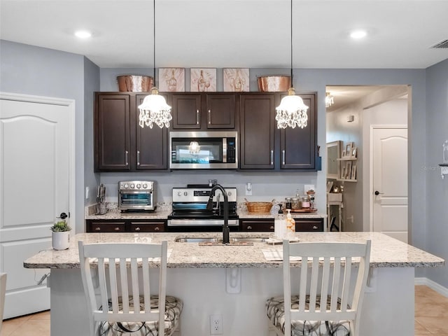 2710 Lilyturf Ct, Tavares, FL 32778 - kitchen featuring appliances with stainless steel finishes, dark brown cabinetry, a kitchen breakfast bar, light tile patterned floors, and recessed lighting