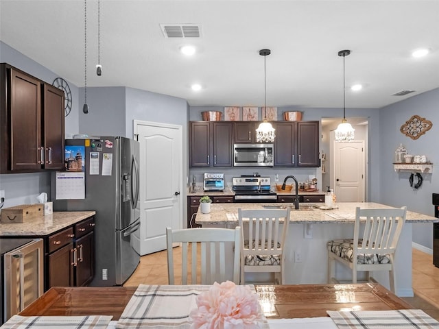 2710 Lilyturf Ct, Tavares, FL 32778 - kitchen featuring stainless steel appliances, beverage cooler, a kitchen bar, dark brown cabinetry, and recessed lighting