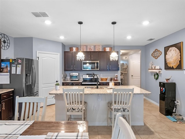 2710 Lilyturf Ct, Tavares, FL 32778 - kitchen with stainless steel appliances, a breakfast bar area, dark brown cabinetry, light tile patterned floors, and light stone countertops