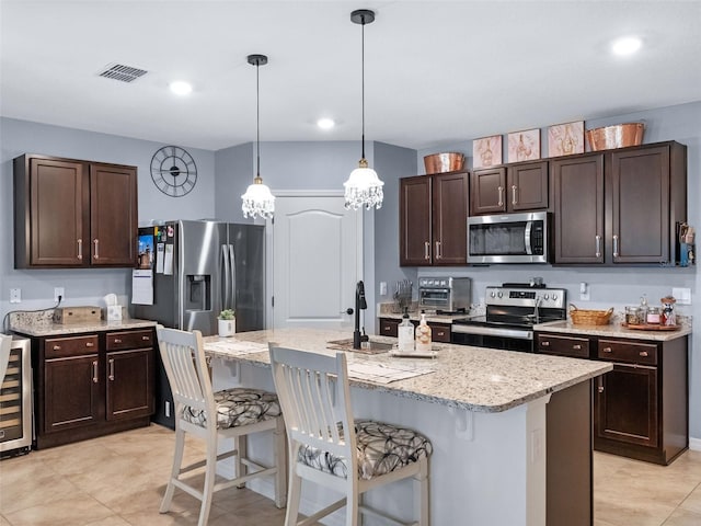 2710 Lilyturf Ct, Tavares, FL 32778 - kitchen with stainless steel appliances, dark brown cabinetry, a breakfast bar, decorative light fixtures, and light tile patterned flooring