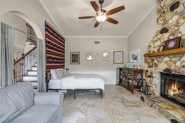 628 Drew Ave, Clermont, FL 34711 - bedroom with ornamental molding, stone finish floors, a stone fireplace, a wainscoted wall, and ceiling fan