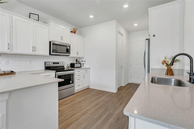 2755 Bobcat Chase Blvd, Oakland, FL 34787 - kitchen with appliances with stainless steel finishes, light wood-style floors, backsplash, white cabinetry, and recessed lighting