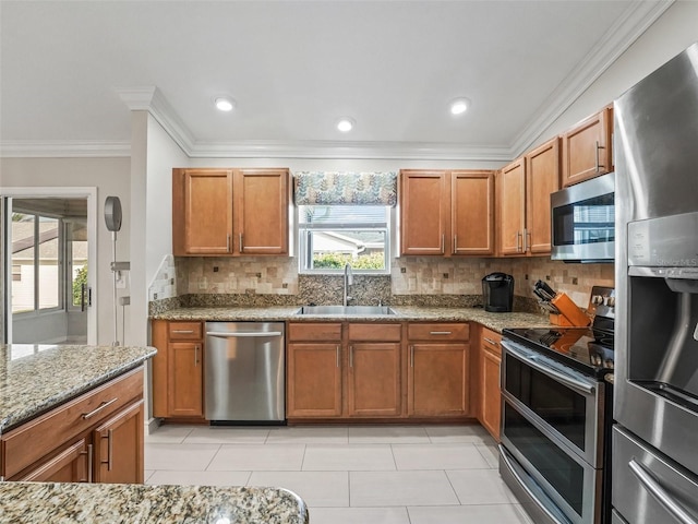 2620 Persimmon Loop, The Villages, FL 32162 - kitchen featuring appliances with stainless steel finishes, tasteful backsplash, light stone countertops, crown molding, and brown cabinets