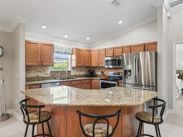 2620 Persimmon Loop, The Villages, FL 32162 - kitchen featuring stainless steel appliances, decorative backsplash, brown cabinetry, a kitchen breakfast bar, and ornamental molding