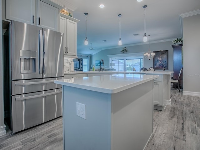 6295 Danielson Loop, The Villages, FL 32163 - kitchen featuring stainless steel refrigerator with ice dispenser, a peninsula, a center island, ornamental molding, and light countertops