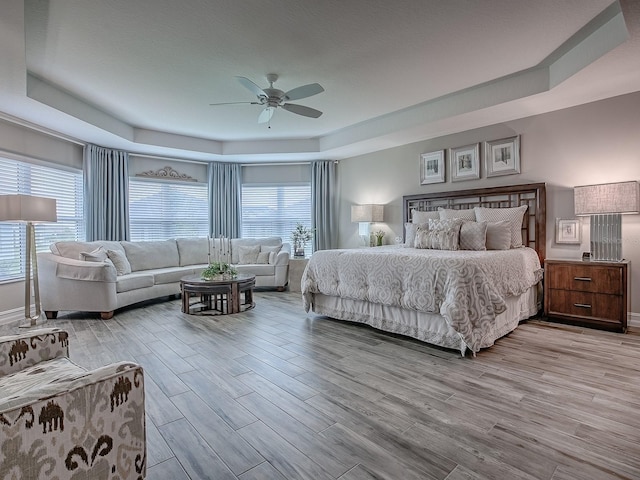 6295 Danielson Loop, The Villages, FL 32163 - bedroom with a tray ceiling, light wood-style flooring, and multiple windows