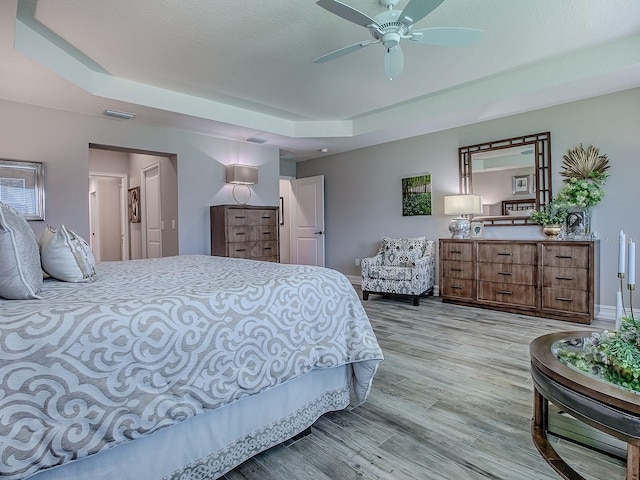6295 Danielson Loop, The Villages, FL 32163 - bedroom with a raised ceiling, wood finished floors, and a ceiling fan