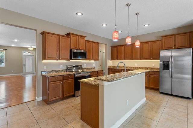 1892 Sanderling Dr, Clermont, FL 34711 - kitchen with appliances with stainless steel finishes, brown cabinets, light stone counters, an island with sink, and recessed lighting