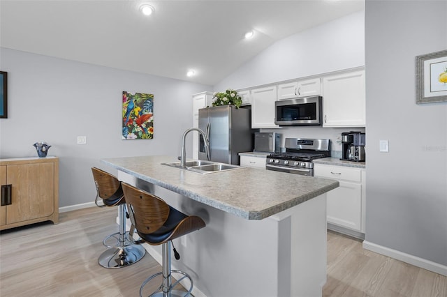 5778 Henry Loop, The Villages, FL 32163 - kitchen with appliances with stainless steel finishes, a kitchen bar, white cabinetry, light wood-style flooring, and lofted ceiling