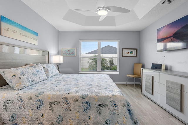 5778 Henry Loop, The Villages, FL 32163 - bedroom featuring a raised ceiling, light wood-style flooring, and a ceiling fan