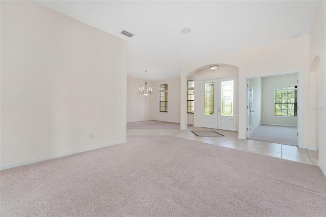 21312 Marsh View Ct, Clermont, FL 34715 - foyer with light colored carpet, a chandelier, light tile patterned flooring, arched walkways, and french doors