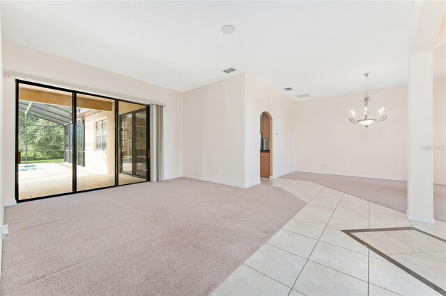 21312 Marsh View Ct, Clermont, FL 34715 - unfurnished room featuring arched walkways, a chandelier, light tile patterned floors, and light colored carpet