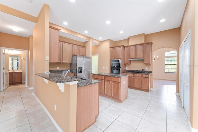 21312 Marsh View Ct, Clermont, FL 34715 - kitchen featuring stainless steel appliances, a peninsula, light tile patterned floors, dark stone counters, and a kitchen island