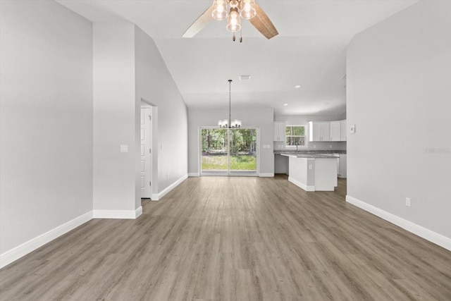 8641 N Stern Way, Citrus Springs, FL 34434 - unfurnished living room featuring a ceiling fan, light wood-type flooring, vaulted ceiling, and a chandelier