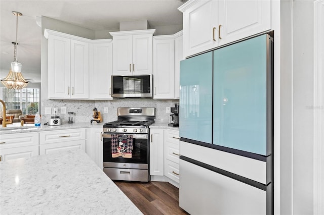 5971 Brittania Blvd, Tavares, FL 32778 - kitchen with appliances with stainless steel finishes, white cabinets, dark wood-type flooring, and decorative backsplash