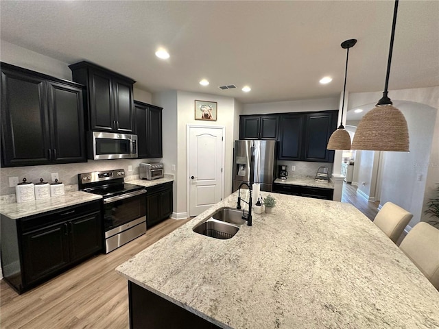384 Summer Squall Rd, Davenport, FL 33837 - kitchen with stainless steel appliances, dark cabinets, light wood-style floors, backsplash, and recessed lighting