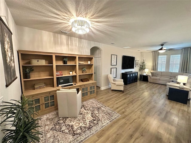 384 Summer Squall Rd, Davenport, FL 33837 - living room featuring arched walkways, wood finished floors, a textured ceiling, a chandelier, and a ceiling fan