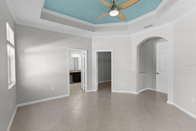 15604 Starlite St, Clermont, FL 34714 - empty room featuring ceiling fan, a tray ceiling, light tile patterned floors, arched walkways, and crown molding