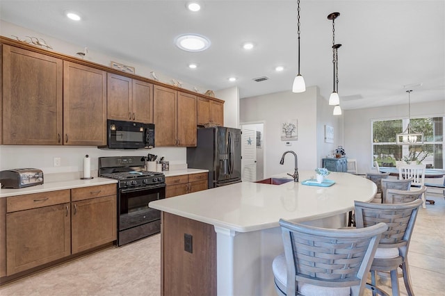 3681 Arlington Ridge Blvd, Leesburg, FL 34748 - kitchen featuring black appliances, a center island with sink, light countertops, a breakfast bar area, and pendant lighting