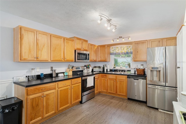149 Shiloh Ave, Lady Lake, FL 32159 - kitchen with stainless steel appliances, light wood-style flooring, dark countertops, and a textured ceiling