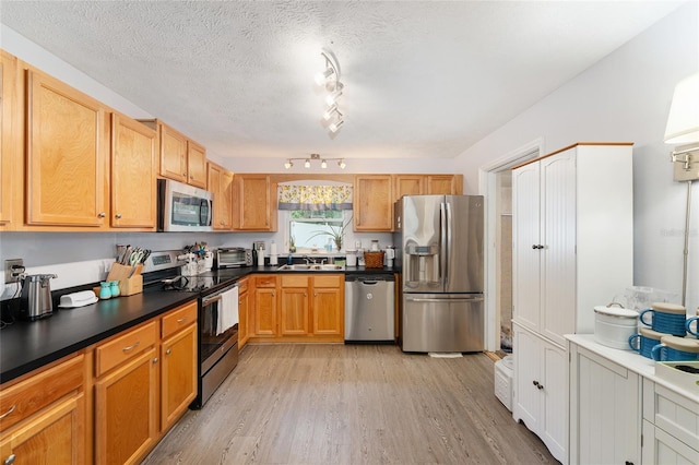 149 Shiloh Ave, Lady Lake, FL 32159 - kitchen featuring appliances with stainless steel finishes, light wood-style floors, dark countertops, and a textured ceiling