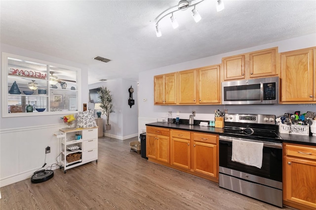 149 Shiloh Ave, Lady Lake, FL 32159 - kitchen featuring appliances with stainless steel finishes, light wood-style floors, dark countertops, a textured ceiling, and ceiling fan