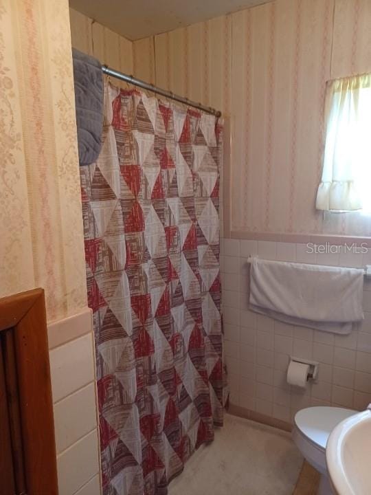 505 Richard St, Leesburg, FL 34748 - full bathroom with wallpapered walls, tile walls, a shower with curtain, and a wainscoted wall