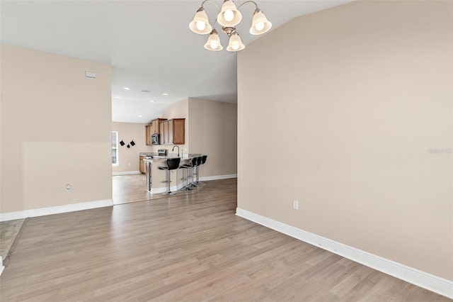 7732 Sloewood Dr, Leesburg, FL 34748 - living area featuring a chandelier, light wood finished floors, and vaulted ceiling