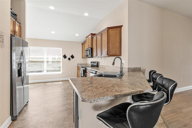 7732 Sloewood Dr, Leesburg, FL 34748 - kitchen with stainless steel appliances, brown cabinetry, lofted ceiling, light countertops, and a peninsula