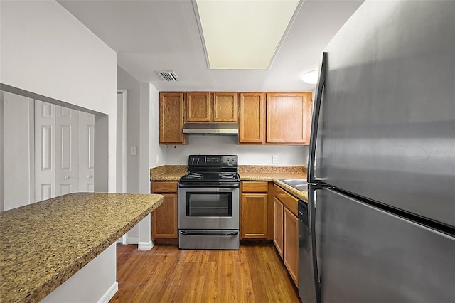 600 W Oak Terrace Dr, Leesburg, FL 34748 - kitchen featuring stainless steel appliances, under cabinet range hood, wood finished floors, and brown cabinets