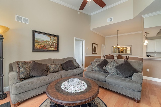 9025 Colby Dr Unit 2121, Fort Myers, FL 33919 - living room featuring a chandelier, light wood-style flooring, crown molding, ceiling fan, and a towering ceiling