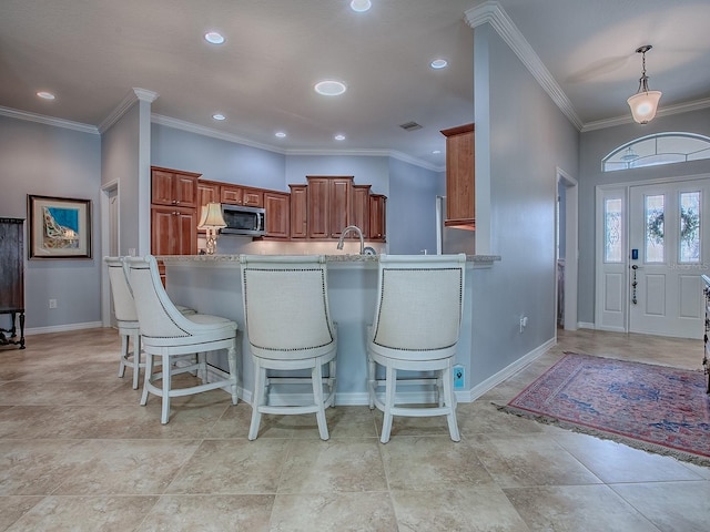 1982 Eldridge Loop, The Villages, FL 32162 - kitchen with stainless steel microwave, a breakfast bar area, brown cabinets, recessed lighting, and a peninsula