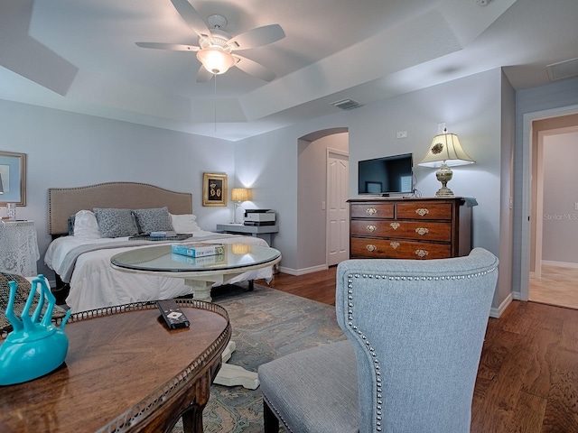 1982 Eldridge Loop, The Villages, FL 32162 - bedroom featuring a tray ceiling, arched walkways, wood finished floors, and ceiling fan