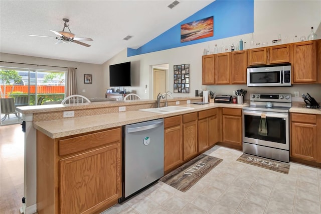 1216 Cheshire St, Groveland, FL 34736 - kitchen with stainless steel appliances, a peninsula, light countertops, brown cabinets, and a ceiling fan
