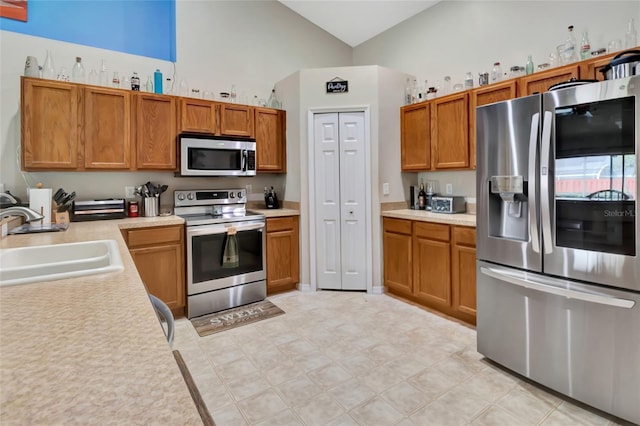 1216 Cheshire St, Groveland, FL 34736 - kitchen featuring appliances with stainless steel finishes, light countertops, brown cabinets, high vaulted ceiling, and light floors