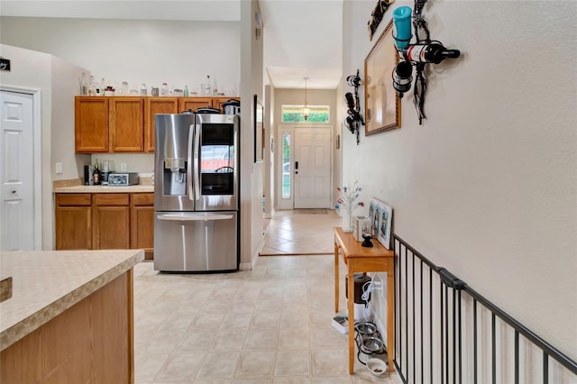 1216 Cheshire St, Groveland, FL 34736 - kitchen featuring stainless steel refrigerator with ice dispenser, brown cabinetry, light countertops, and light tile patterned floors