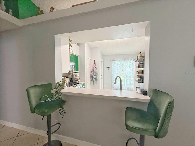 15349 Lafite Ln, Clermont, FL 34714 - kitchen with stainless steel microwave, tile patterned flooring, a peninsula, range, and a kitchen breakfast bar