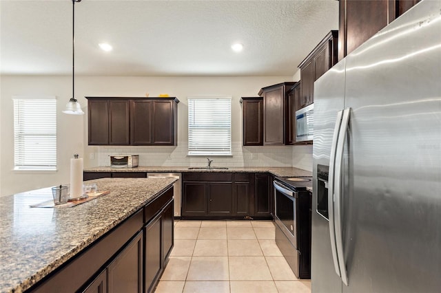 120 Citrus Isle St, Davenport, FL 33837 - kitchen with stainless steel appliances, dark brown cabinets, tasteful backsplash, light tile patterned floors, and recessed lighting