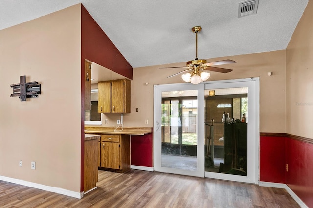 461 Kee St, Apopka, FL 32712 - kitchen with brown cabinets, ceiling fan, wood finished floors, vaulted ceiling, and light countertops