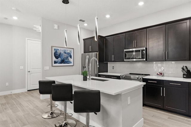 2163 White Feather Loop, Oakland, FL 34787 - kitchen featuring stainless steel appliances, a center island with sink, decorative backsplash, a breakfast bar area, and light wood-type flooring