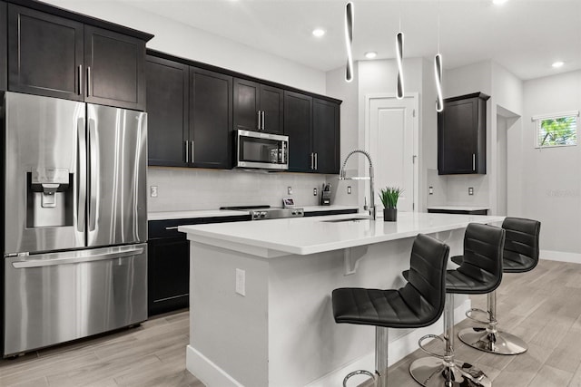 2163 White Feather Loop, Oakland, FL 34787 - kitchen with stainless steel appliances, light wood-type flooring, backsplash, an island with sink, and recessed lighting