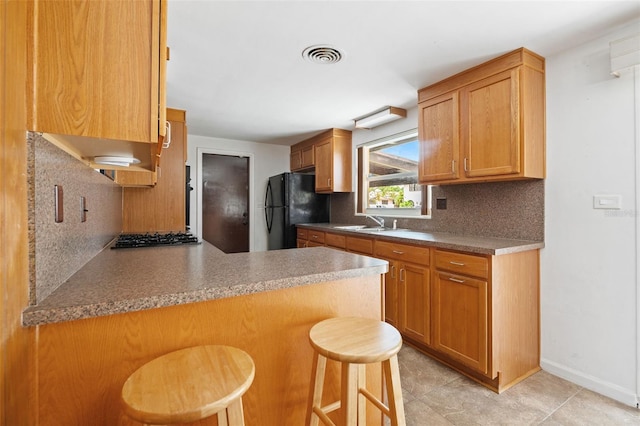 138 W 52nd St, Hialeah, FL 33012 - kitchen featuring freestanding refrigerator, tasteful backsplash, stainless steel gas cooktop, and a peninsula