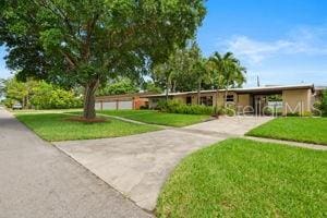138 W 52nd St, Hialeah, FL 33012 - view of home's community featuring a lawn, an attached carport, and driveway