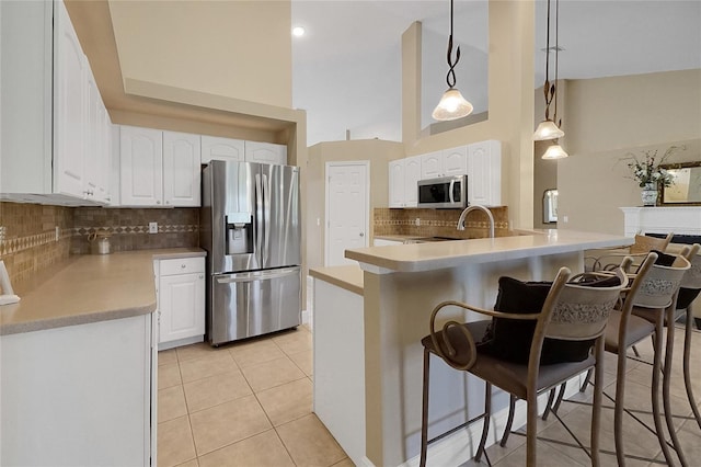 5349 Grove Mnr, Lady Lake, FL 32159 - kitchen featuring stainless steel appliances, a kitchen breakfast bar, light tile patterned flooring, backsplash, and white cabinets