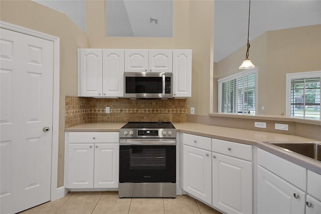 5349 Grove Mnr, Lady Lake, FL 32159 - kitchen with appliances with stainless steel finishes, lofted ceiling, light tile patterned floors, decorative backsplash, and light countertops