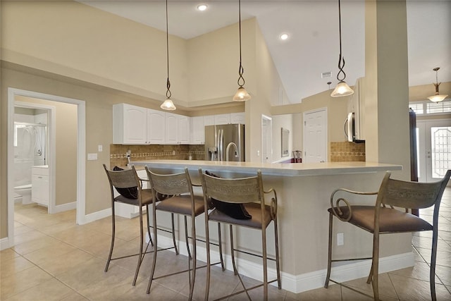 5349 Grove Mnr, Lady Lake, FL 32159 - kitchen with stainless steel appliances, a breakfast bar, white cabinetry, tasteful backsplash, and high vaulted ceiling