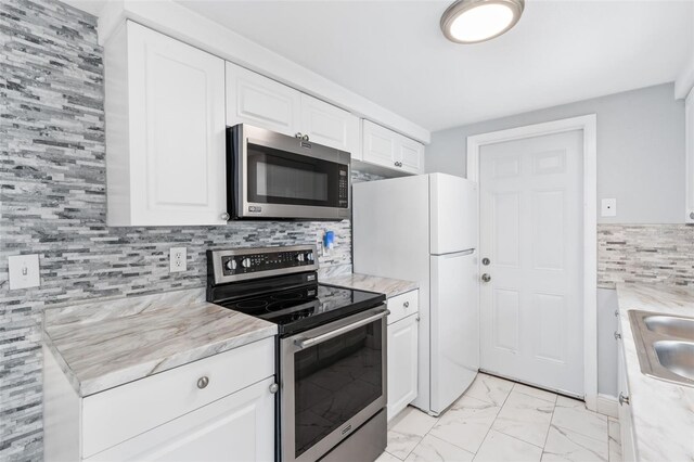 11326 Yellowwood Ln, Port Richey, FL 34668 - kitchen featuring appliances with stainless steel finishes, light marble finish flooring, white cabinetry, and tasteful backsplash